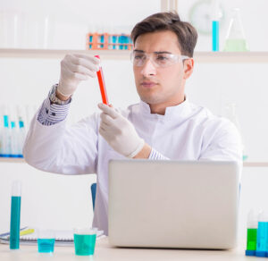 A man in a lab coat is holding a test tube for Water Quality Testing.